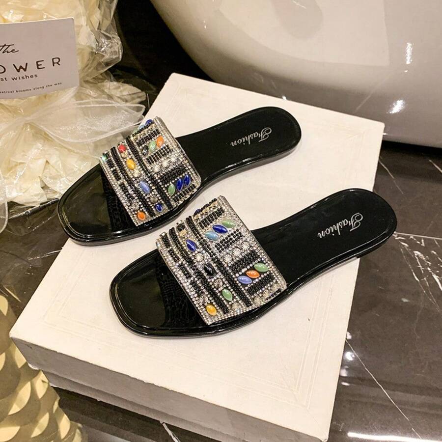 4 media show black and beige flat slide sandals with single wide vamp band, glossy footbed, rounded square toe, rhinestones, pearls, multicolor oval gems, bead rows and floral crystal clusters. image 2