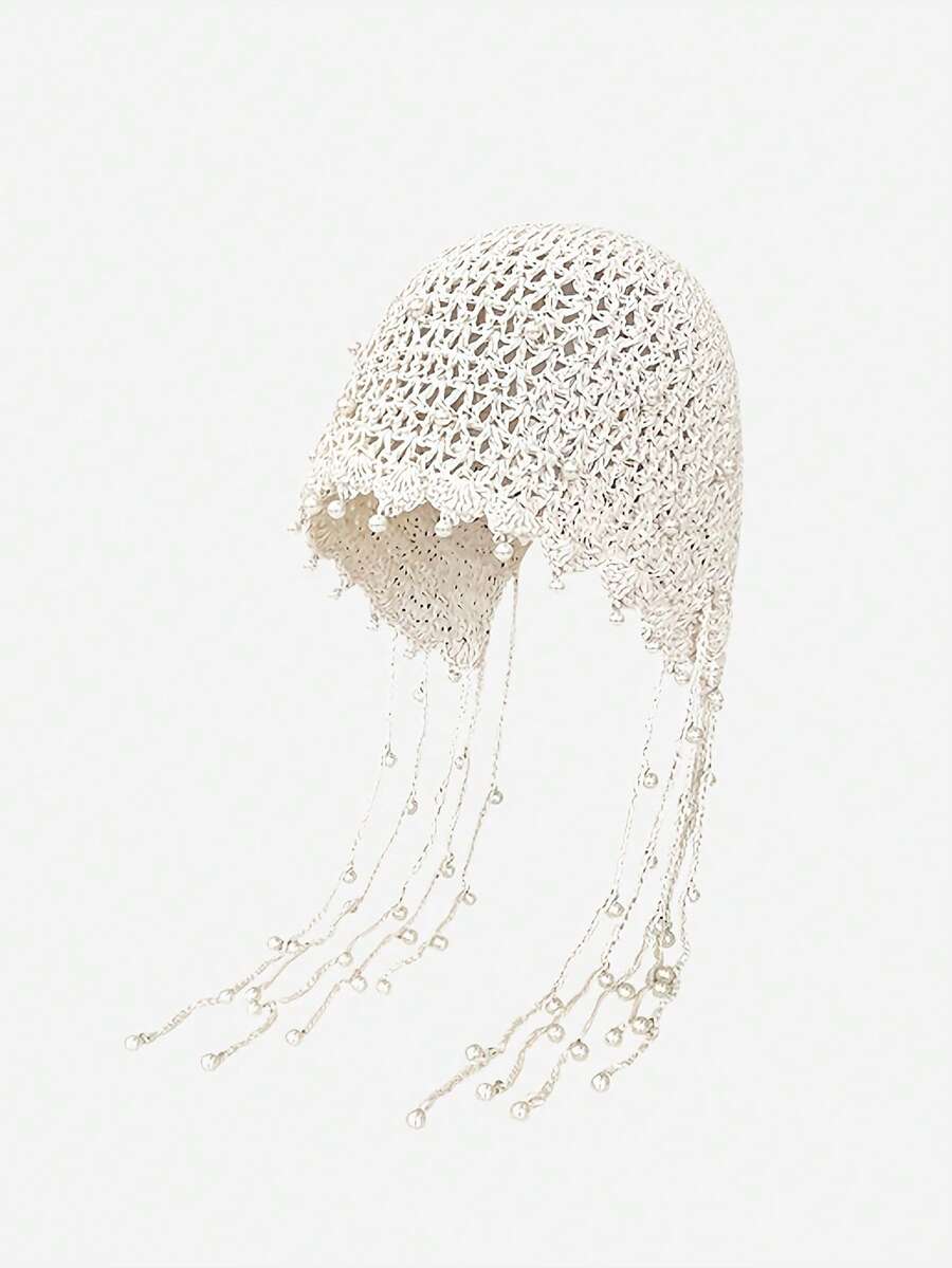 Model wearing ivory openwork crochet cap with long dangling pearl-like beads