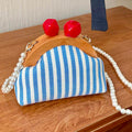 Front view of blue striped mini kiss lock bag with pearl strap and wood frame