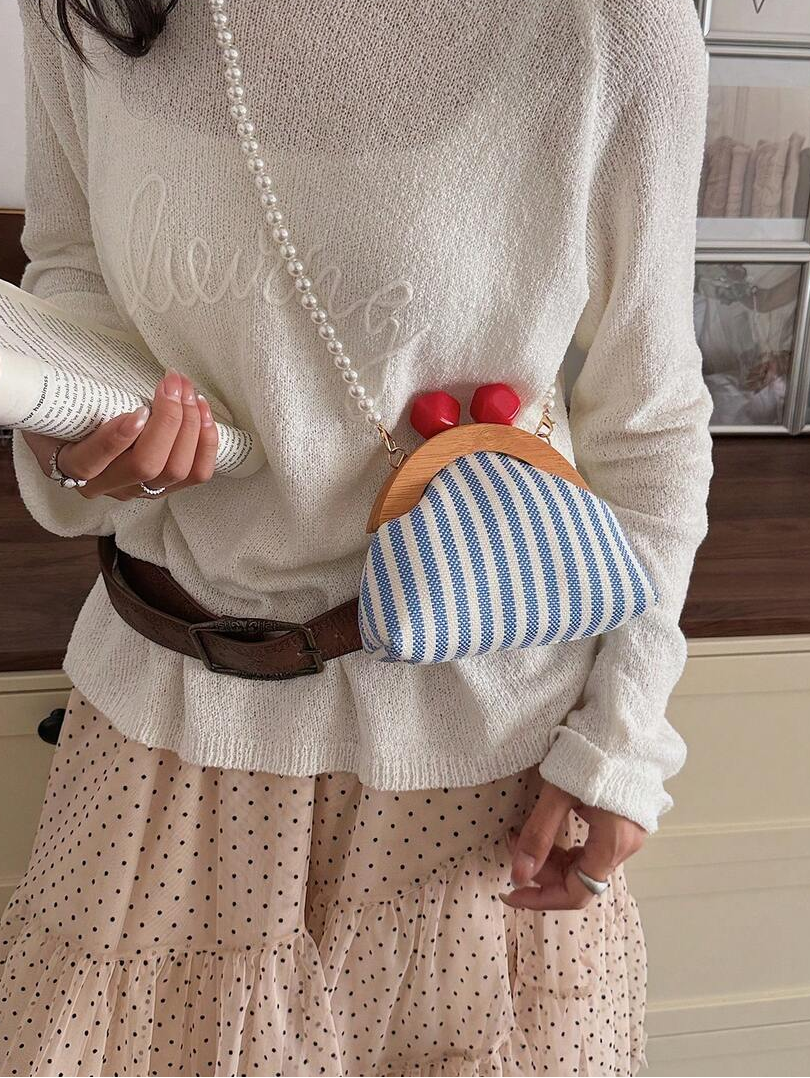 Worn crossbody view of blue striped mini pouch bag with pearl shoulder strap