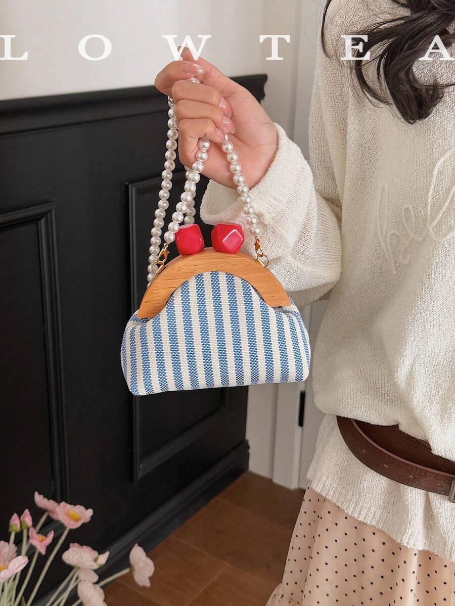 Handheld view of retro striped kiss lock bag with pearl strap and gold hardware