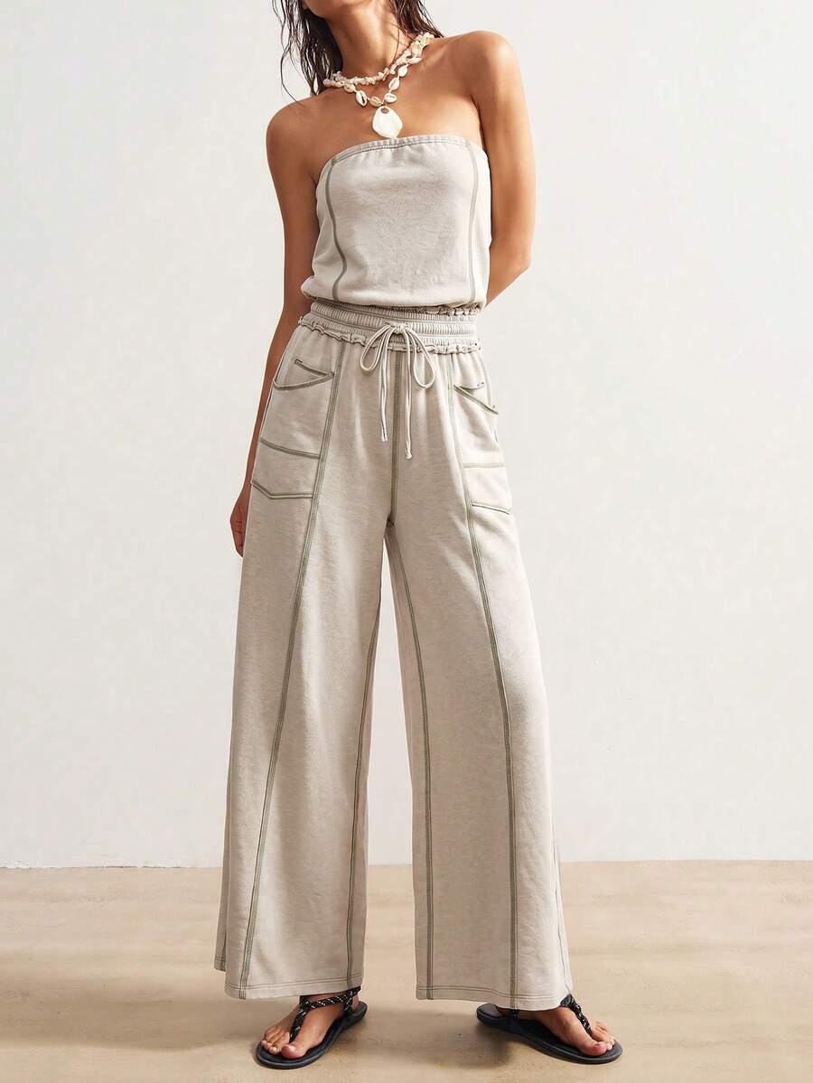 Front view of light stone strapless wide-leg jumpsuit with contrast seams and utility pockets