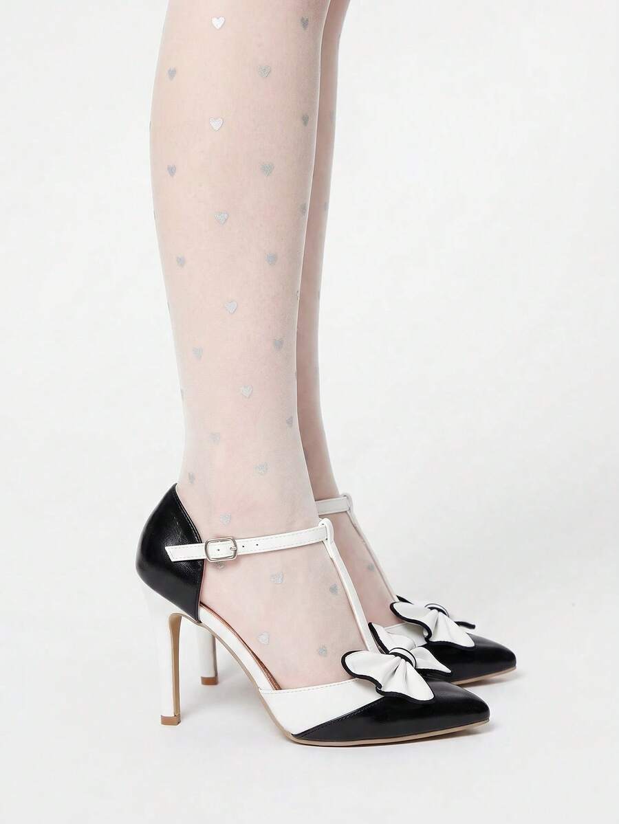 Pair of black and white bow pumps showing pointed toes and slim stiletto heels