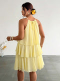 Back view of pale yellow tiered halter dress with tie detail