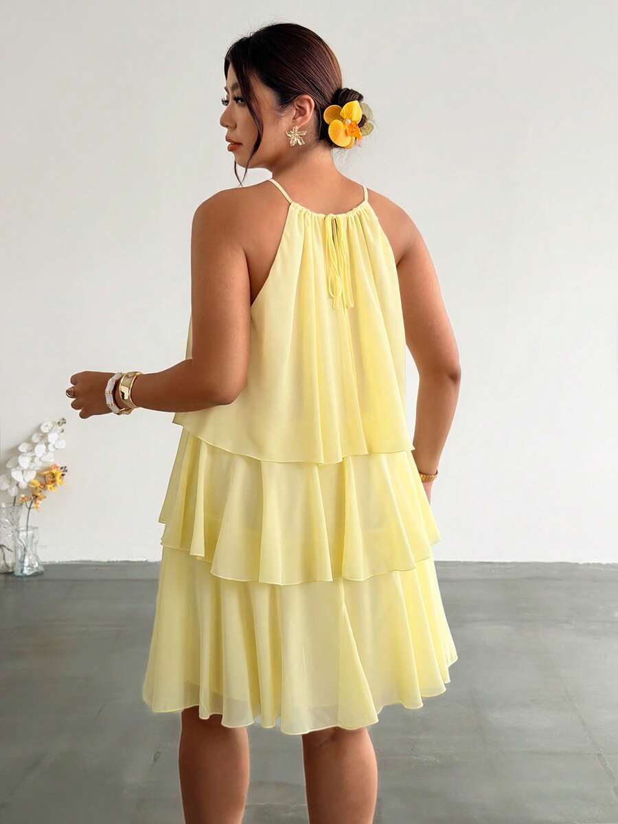 Back view of pale yellow tiered halter dress with tie detail