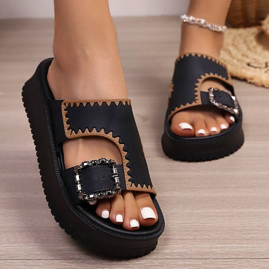 Black platform slide sandals with tan trim, open toe, and jeweled buckle