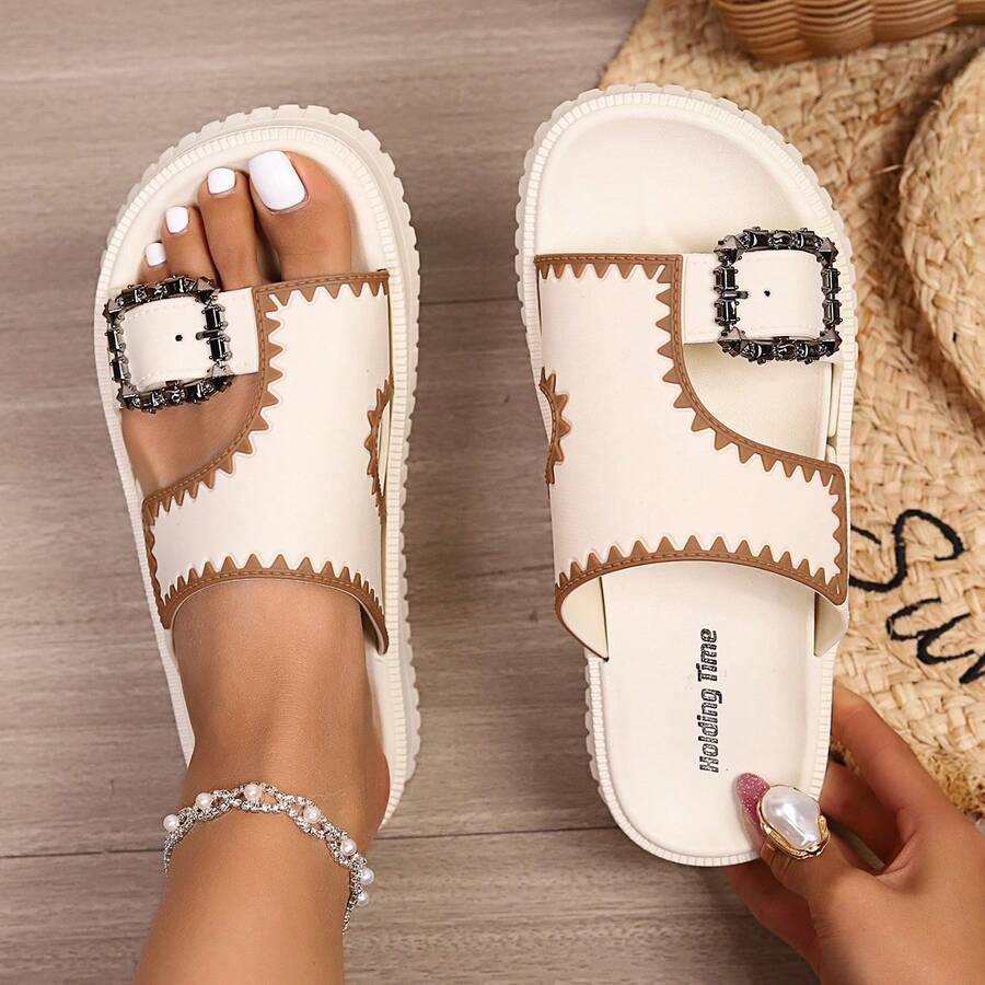 Cream white platform slide sandals with tan trim and decorative buckle