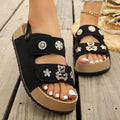4 media show cream/beige and black platform slingback comfort sandals with two wide cutout front straps, back heel strap snap button, rhinestone flower studs, pearl-like studs, teddy-bear charm, thick tan platform and black ridged tread. image 3