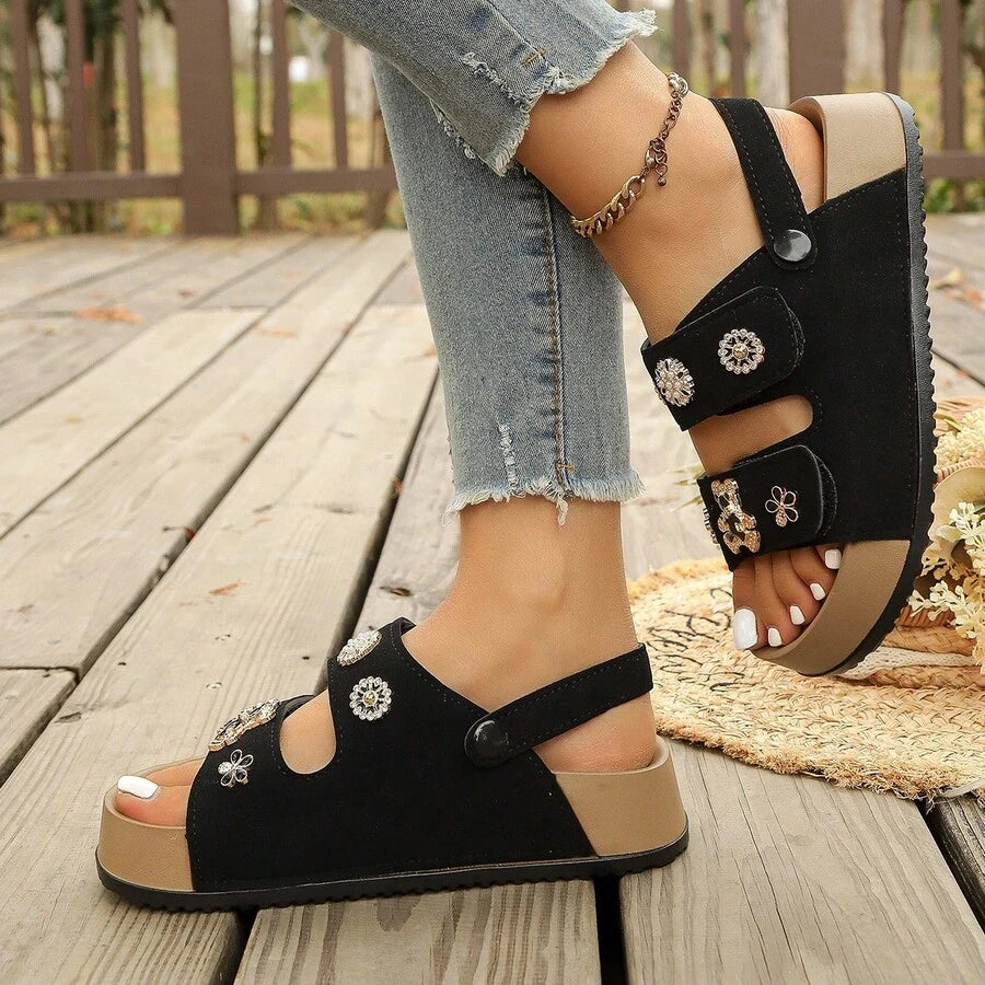 4 media show cream/beige and black platform slingback comfort sandals with two wide cutout front straps, back heel strap snap button, rhinestone flower studs, pearl-like studs, teddy-bear charm, thick tan platform and black ridged tread. image 4