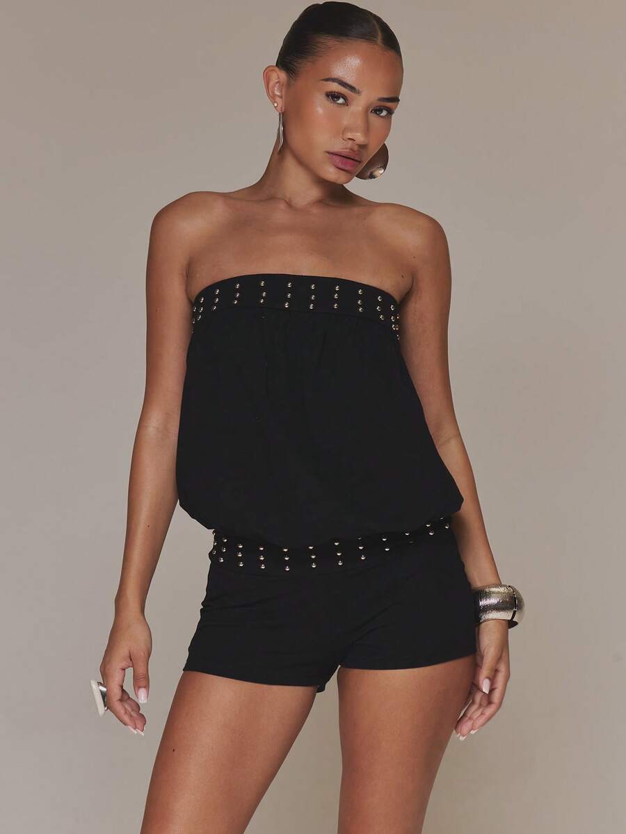 Cropped front three-quarter view of black strapless romper with studded neckline and waist