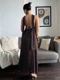 Back view of brown polka dot backless maxi dress with spaghetti straps and tie detail