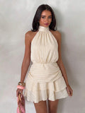 Front view of apricot halter mini dress with gathered waist and layered hem