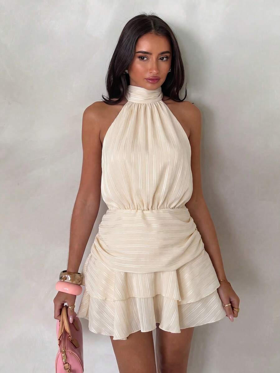 Front view of apricot halter mini dress with gathered waist and layered hem