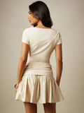 Back view of apricot drop waist mini dress with fitted bodice and flared frill hem
