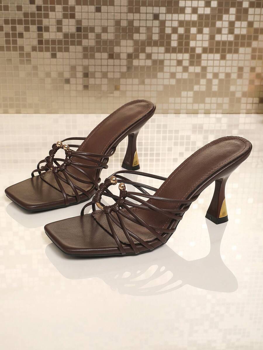 Front product view of brown woven-strap heeled sandals with open square toes and ring ornaments