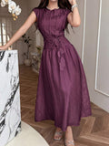 Front view of dark plum belted A-line maxi dress in elegant interior