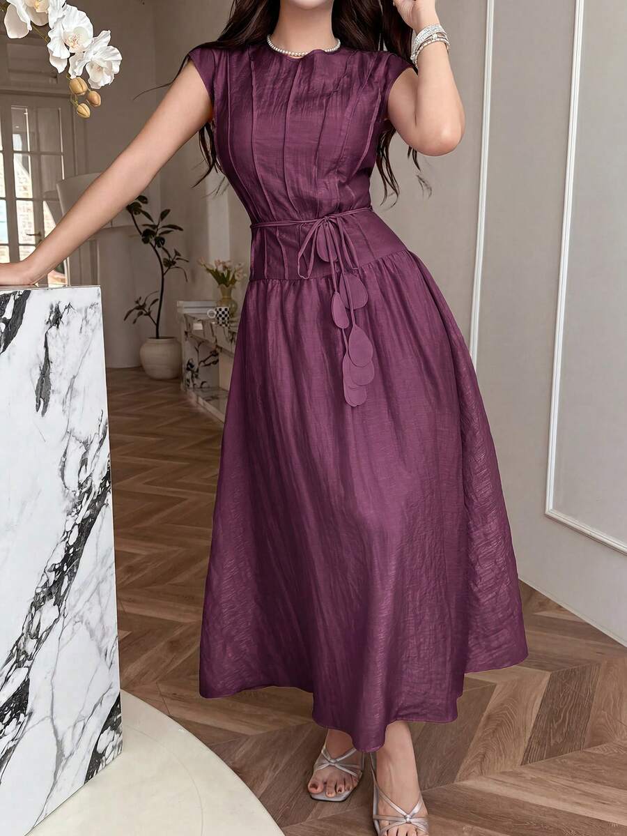 Front view of dark plum belted A-line maxi dress in elegant interior
