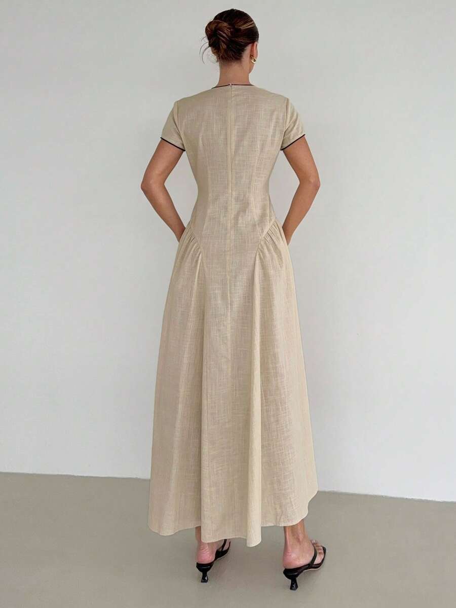Street front view of apricot cotton retro maxi dress with short sleeves, black piping, and lace-up neckline