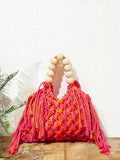 Orange and pink crochet beach bag on floor with hollow weave long tassels and cream bead handle