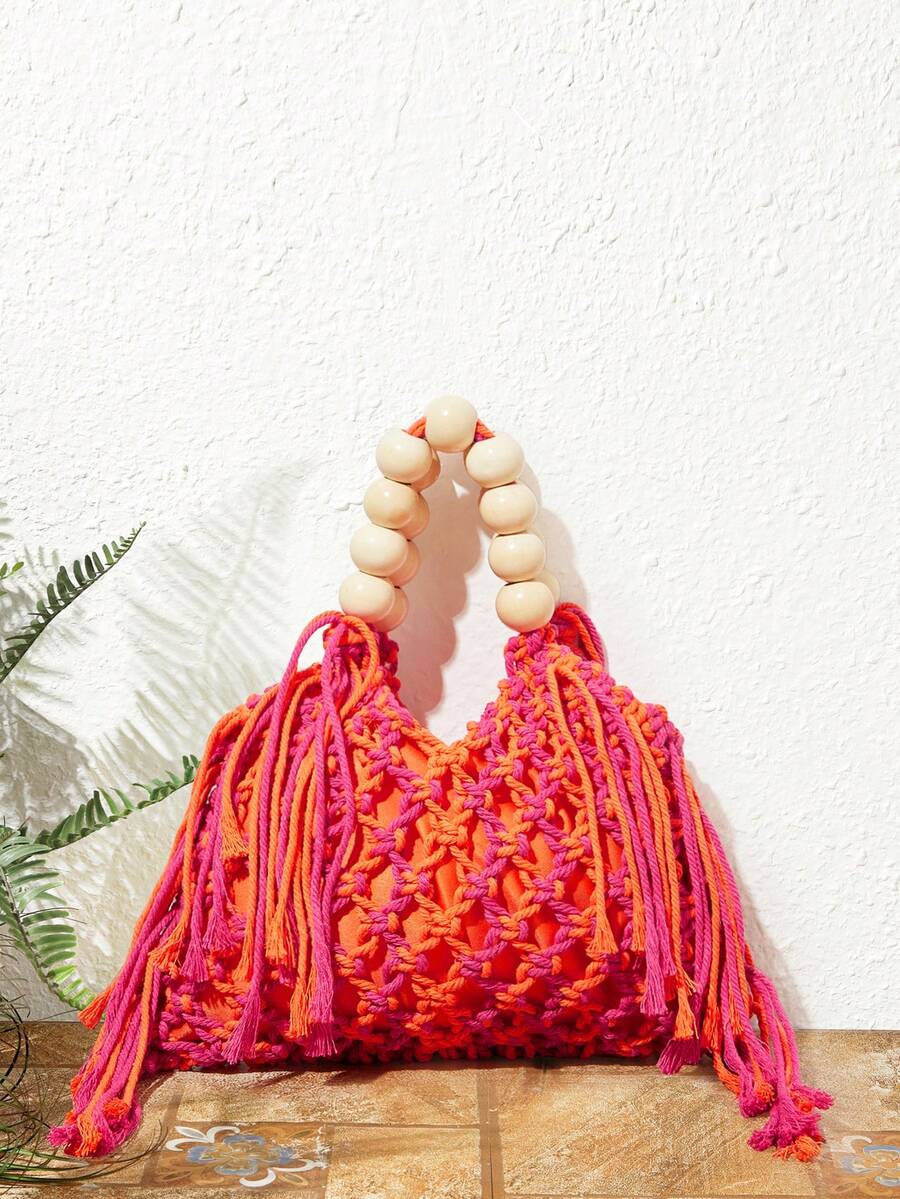 Orange and pink crochet beach bag on floor with hollow weave long tassels and cream bead handle