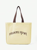 Close view of pale yellow logo tote showing reinforced strap stitching