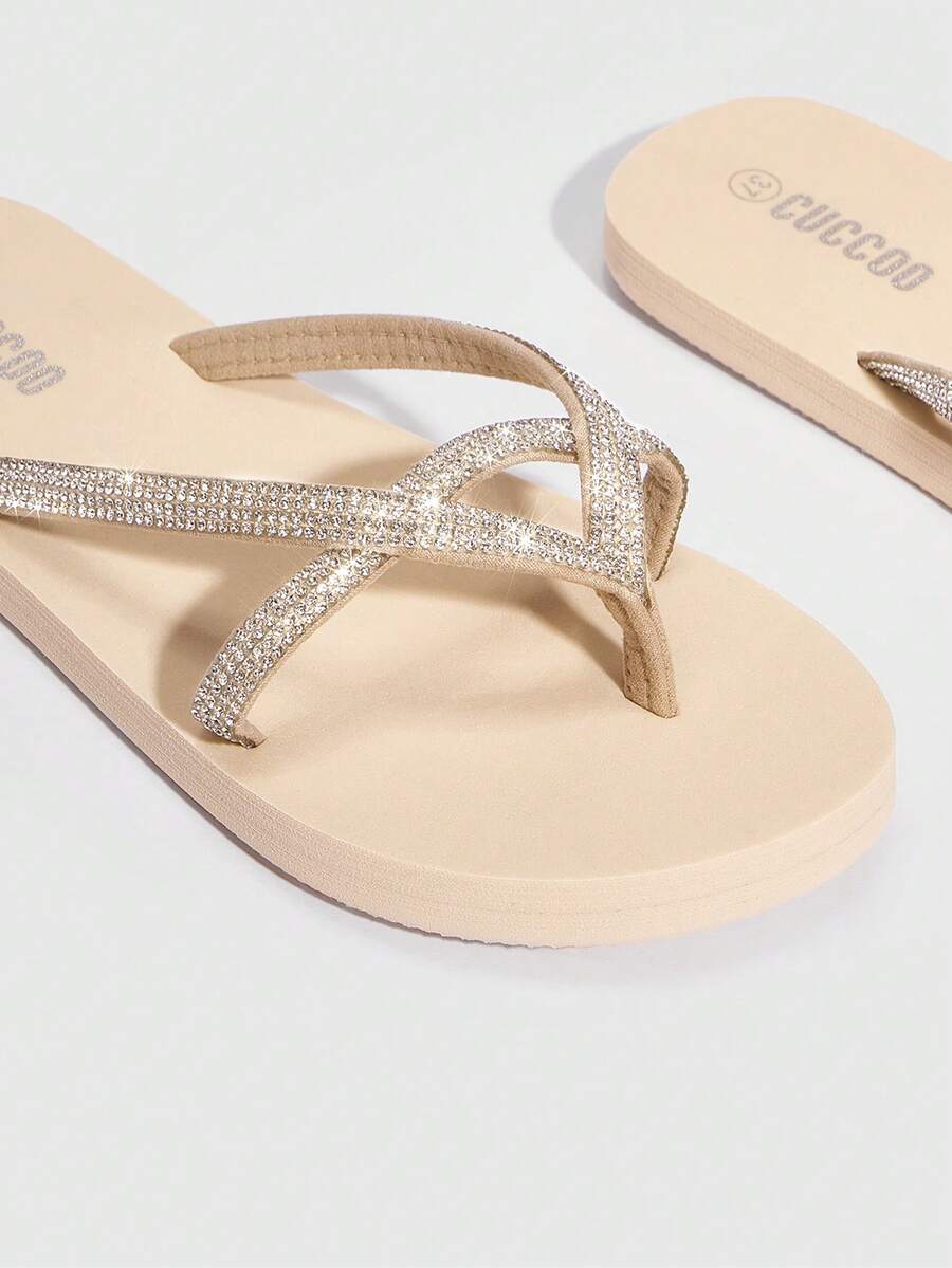 Close-up studio view of beige jeweled thong flip flops as a pair
