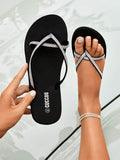 Top view of black rhinestone flip flops held and worn with white pedicure