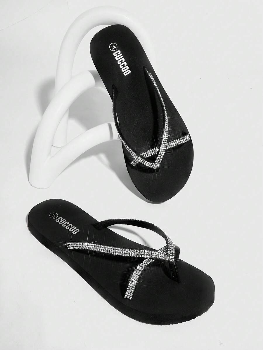 Oblique studio view of black rhinestone thong flip flops as a pair