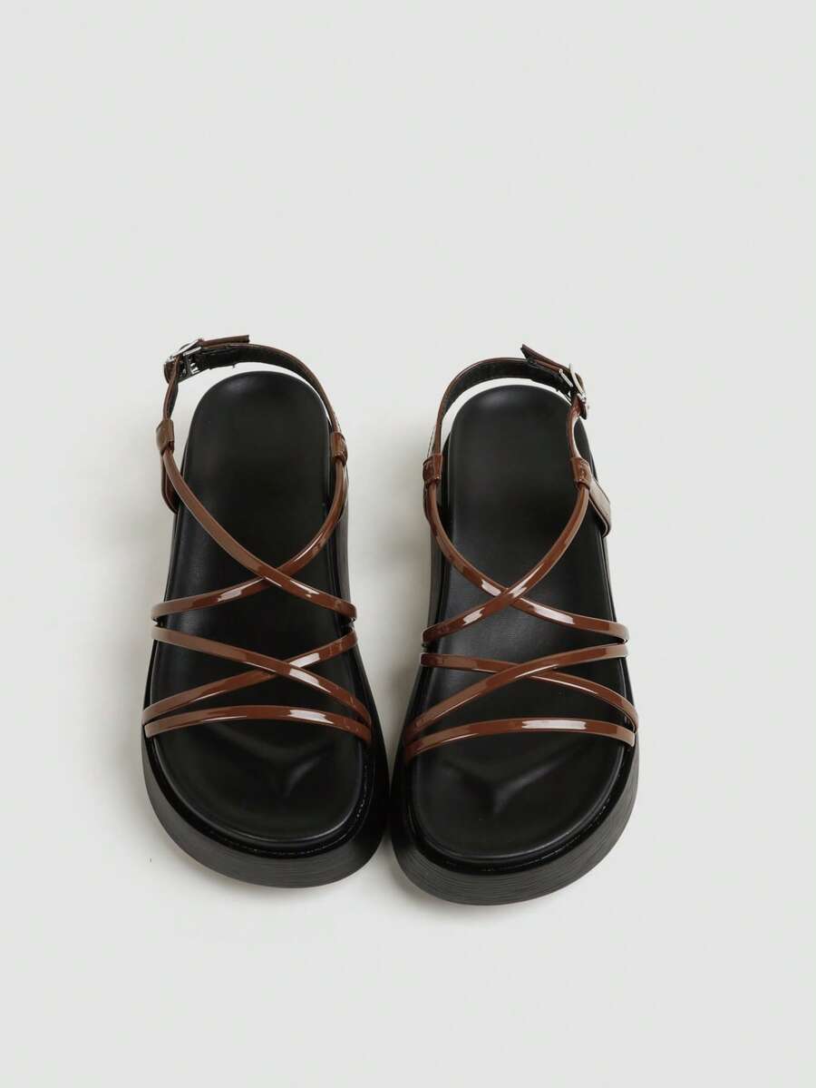 Brown glossy platform sandals top view showing crossed forefoot straps and black sole