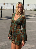 Front three-quarter view of green floral velvet mini dress with deep V-neck and bell sleeves