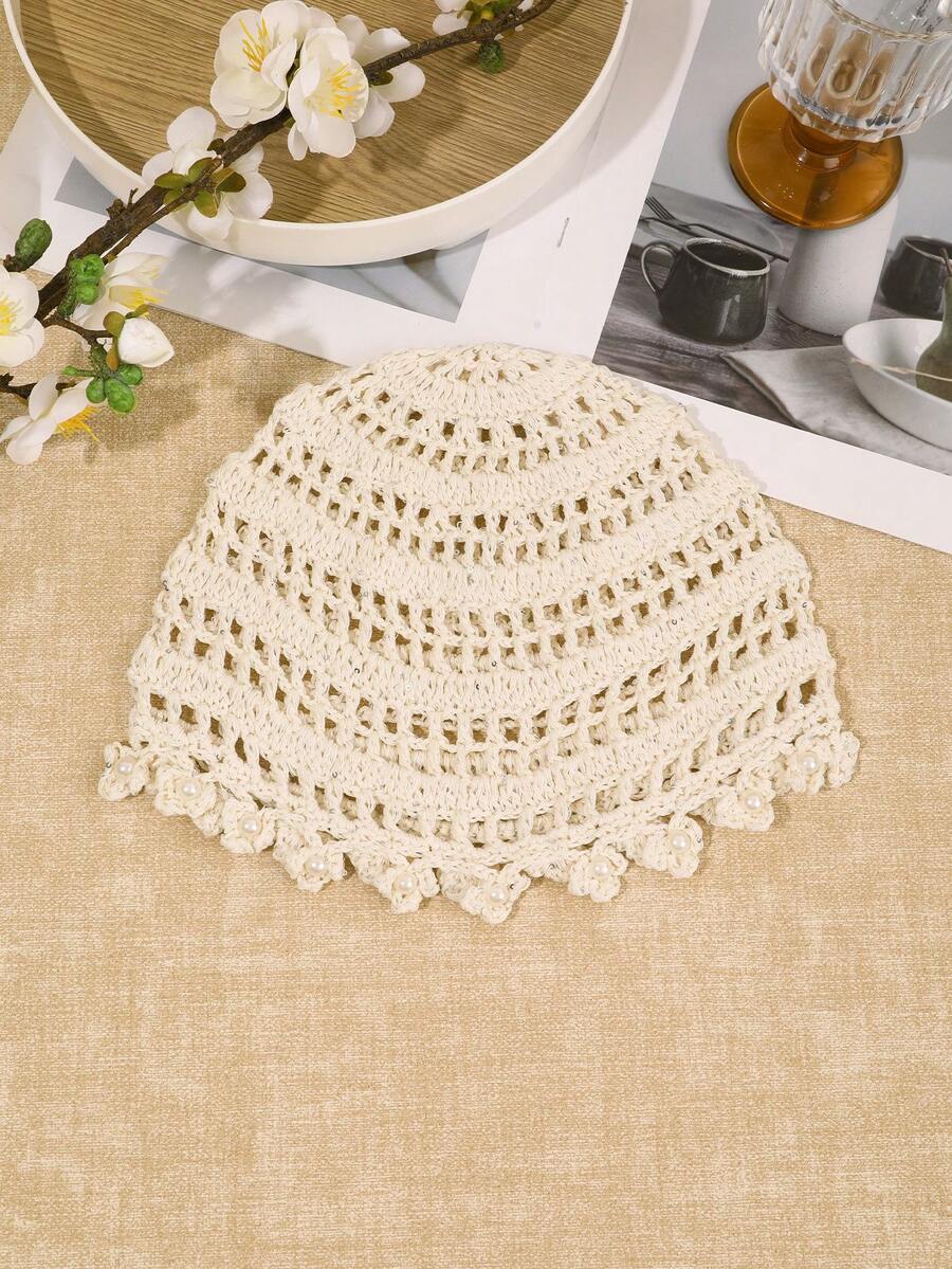 Detail view of ivory crochet hat with pearl centered flower appliques