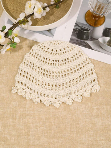 Detail view of ivory crochet hat with pearl centered flower appliques