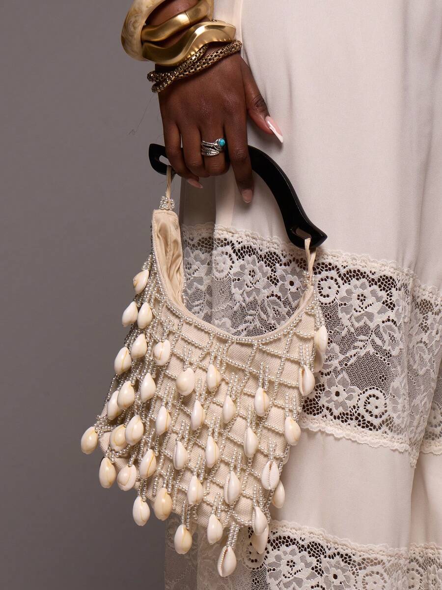 Cream shell beaded mini hobo bag with curved black handle and cowrie fringe