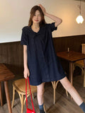 Full front lifestyle view of dark-indigo short-sleeve denim smock dress with flared mini hem