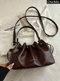 Detail view of brown drawstring shoulder bag with wood beads and silver hardware