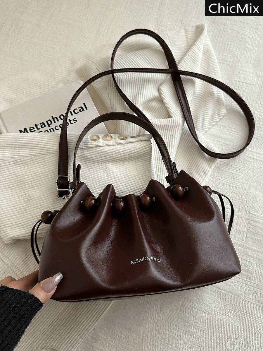 Detail view of brown drawstring shoulder bag with wood beads and silver hardware