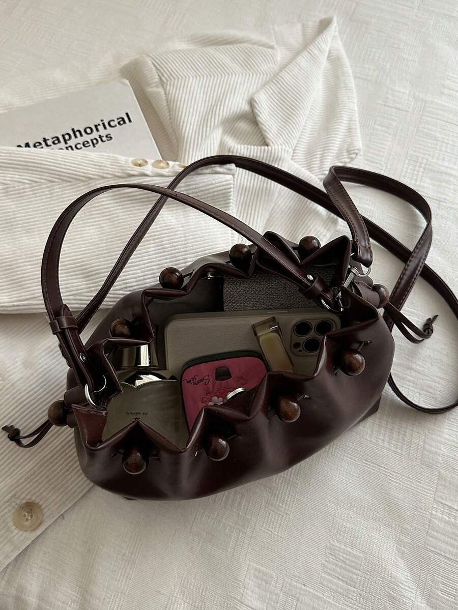 Brown drawstring shoulder bag showing side knots and flat base