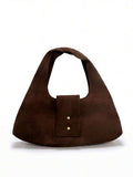 Detail view of brown fold-over handbag showing soft suede texture and minimal hardware