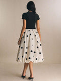 Back view black top with white polka-dot bubble skirt and midi length