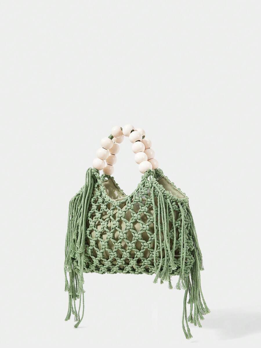 Green crochet beach bag angled view with open knit body fringe sides and bead handle