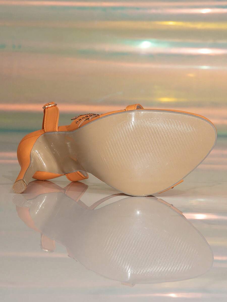 Bottom view orange stiletto sandal showing beige textured outsole and heel tip