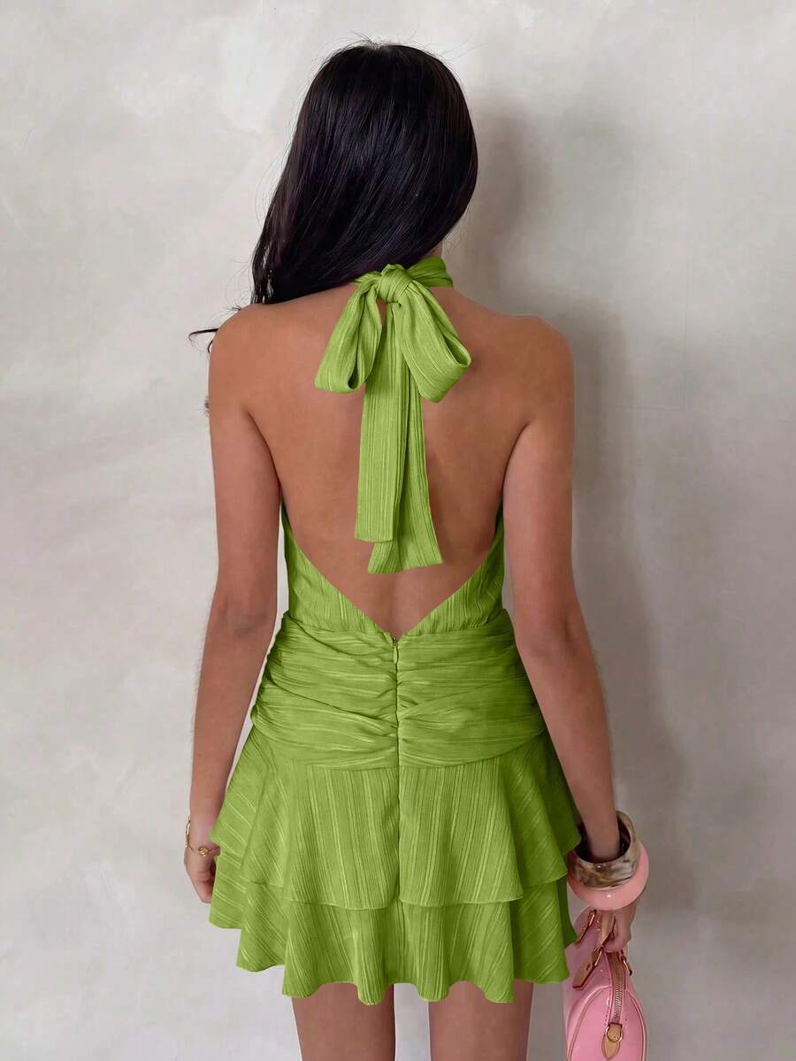 Back view of green halter mini dress with tied neck and open V back