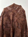 Close-up of semi-sheer coffee brown knit fabric with raised floral jacquard pattern
