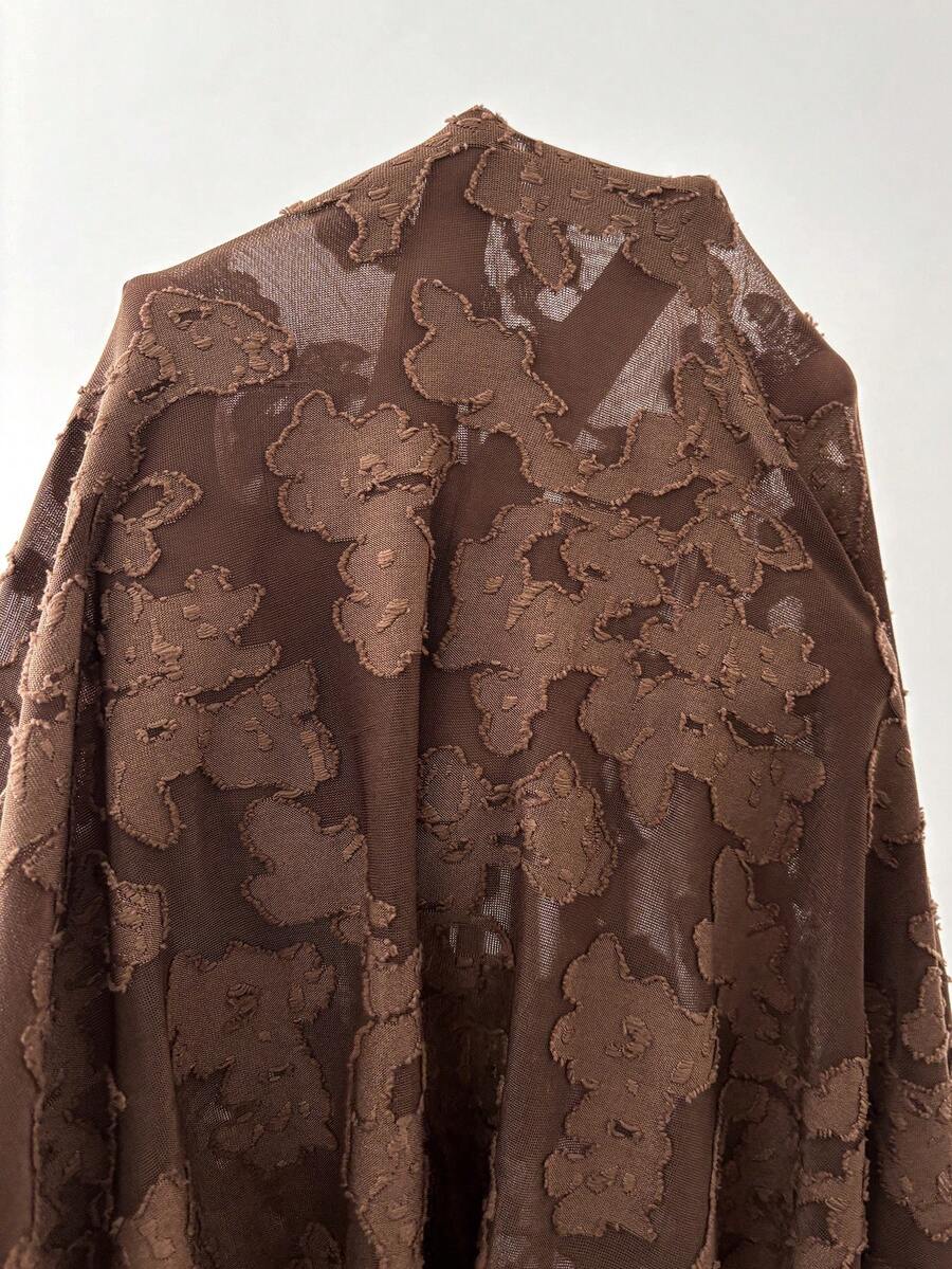 Close-up of semi-sheer coffee brown knit fabric with raised floral jacquard pattern