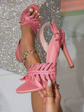 Pink rhinestone leaf cutout stiletto sandals hand held close-up with clear side panel