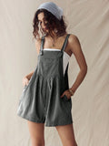 Front three-quarter view of black-and-white striped overall romper with hands in pockets