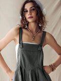 Close front view of black striped romper with square bib, buttons and gathered lower panel