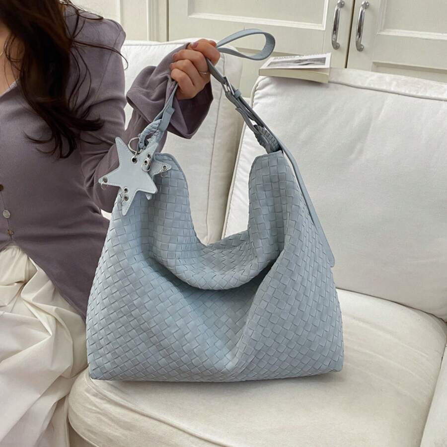 Lifestyle view of baby blue woven shoulder bag with slouchy crescent shape and star charm