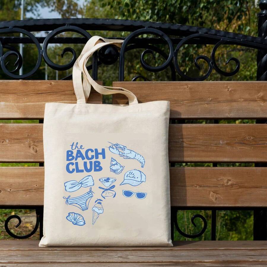 Outdoor bench view of white canvas wedding tote bag with blue beach graphic and twin handles