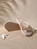 Three-quarter view of blush beige platform flip flops showing textured outsole, shell charms and starfish detail